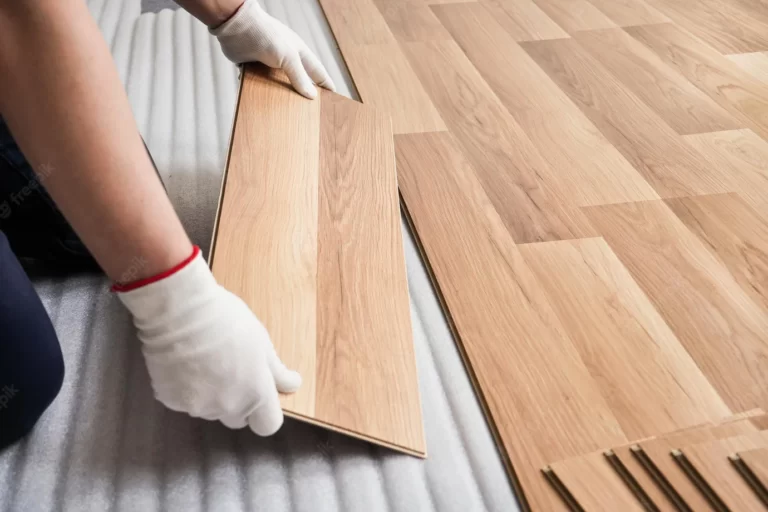 installing-laminated-floor-detail-man-hands-with-white-gloves-fitting-wooden-tile-white-foam-base-layer_692357-5450