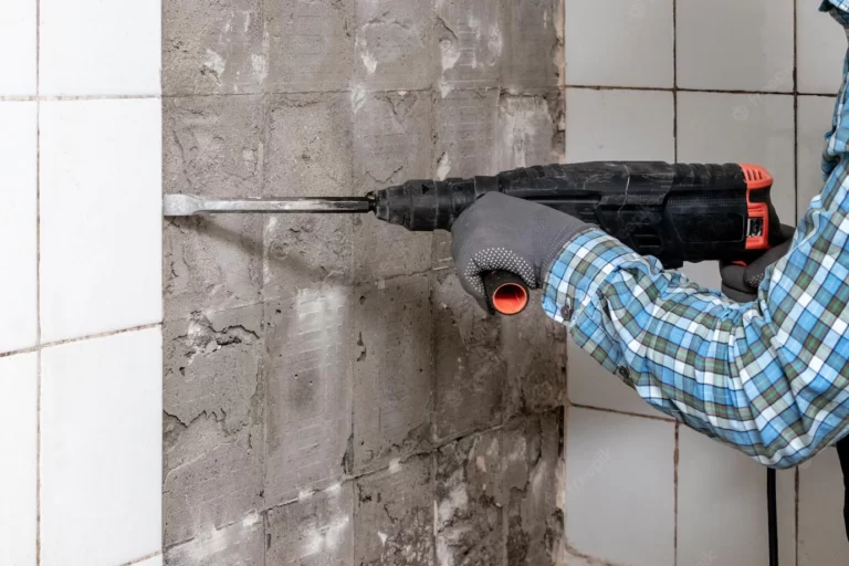 worker-dismantles-tiles-from-bathroom-wall-with-help-perforator_199743-13500